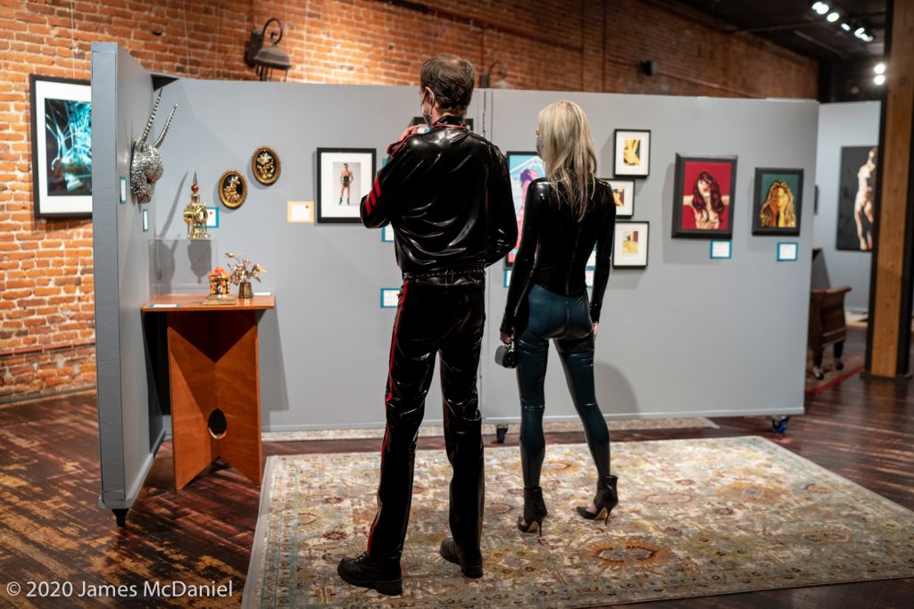 Two patrons in latex viewing art at Gallery Erato.